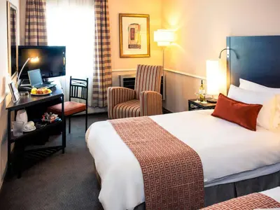 a hotel room with a bed and a chair at Mercure Johannesburg Midrand in Midrand