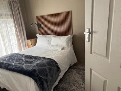 a bedroom with a bed with white pillows and a window at BEE Boutique Lodge in Nelspruit