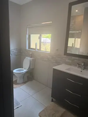 a bathroom with a toilet and a sink and a window at BEE Boutique Lodge in Nelspruit