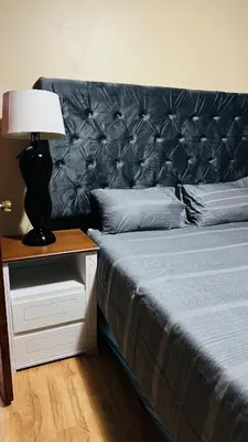 a bed with a black headboard and a table with a lamp at Makhuvha Tshilivho Luxury House in Thohoyandou