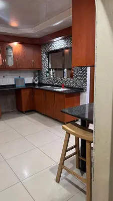 a kitchen with wooden cabinets and a black counter top at Makhuvha Tshilivho Luxury House in Thohoyandou