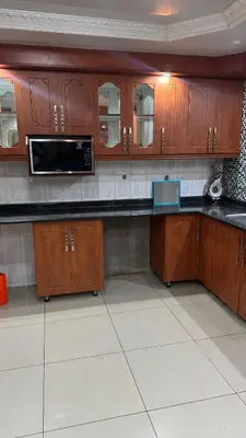 a kitchen with wooden cabinets and a microwave at Makhuvha Tshilivho Luxury House in Thohoyandou