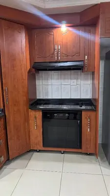 a kitchen with a black microwave and wooden cabinets at Makhuvha Tshilivho Luxury House in Thohoyandou