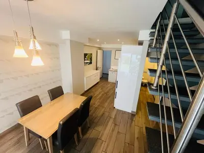 a dining room with a table and chairs and a staircase at Regency Menlyn, 2 Bed Spacious Double Storey, New! in Pretoria