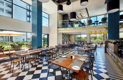 a restaurant with tables and chairs in a building at Regency Menlyn, 2 Bed Spacious Double Storey, New! in Pretoria
