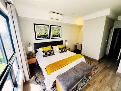 a bedroom with a large bed with yellow pillows at Regency Menlyn, 2 Bed Spacious Double Storey, New! in Pretoria