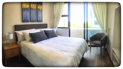 a bedroom with a bed and a chair and a window at Regency Menlyn Hotel 1Bed Apartment LongStay 32 percent off in Pretoria