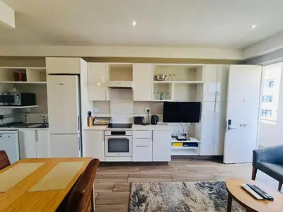 a kitchen with white appliances and a table in a room at Regency Menlyn Hotel 1Bed Apartment LongStay 32 percent off in Pretoria
