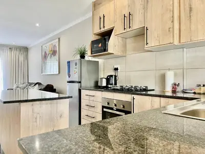 a kitchen with wooden cabinets and a stainless steel refrigerator at Midrand 2-Bedroom Oasis in Glen Austin in Midrand