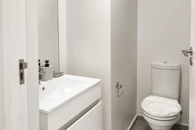 a white bathroom with a toilet and a sink at The Nest in Midrand