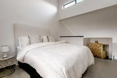 a white bedroom with a large white bed and a window at The Nest in Midrand