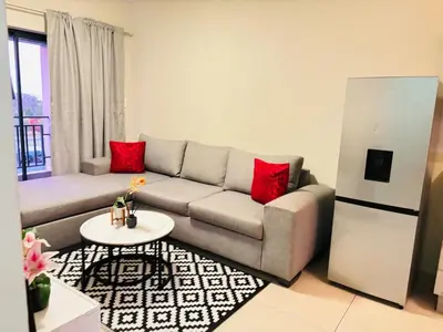 a living room with a gray couch and red pillows at Cozy getaway in Midrand