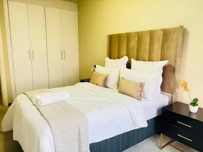 a bedroom with a large bed with white sheets and pillows at Cozy getaway in Midrand