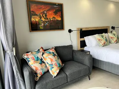 a bedroom with a couch and a painting and a bed at Entire Apartment in Midrand, South Africa in Midrand