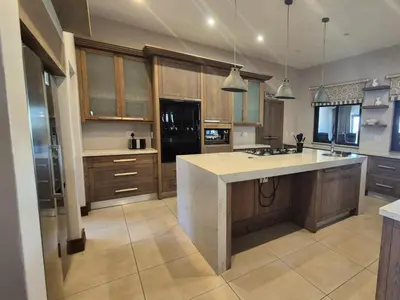 a kitchen with wooden cabinets and a large island at Highlands Retreat Lodge In Highland Gate Golf and Trout Estate 1135 in Dullstroom
