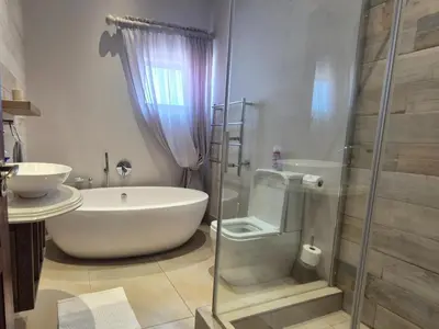 a bathroom with a tub and a glass shower at Highlands Retreat Lodge In Highland Gate Golf and Trout Estate 1135 in Dullstroom