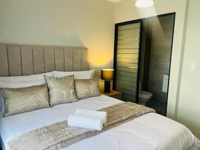 a bedroom with a large white bed and a lamp at 2 Bed Lux apartment at The Blyde in Pretoria