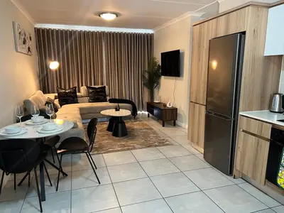 a living room with a couch and a table with chairs at 2 Bed Lux apartment at The Blyde in Pretoria