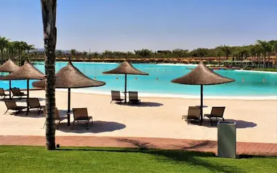 a pool with chairs and umbrellas on a beach at 2 Bed Lux apartment at The Blyde in Pretoria