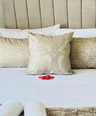 a white bed with pillows and a red rose on it at 2 Bed Lux apartment at The Blyde in Pretoria