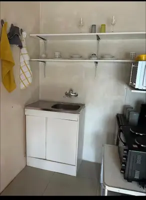 a small white kitchen with a sink and shelves at Mary's spacious and homely place in Polokwane