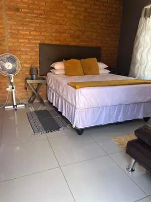 a bedroom with a bed and a brick wall at Mary's spacious and homely place in Polokwane