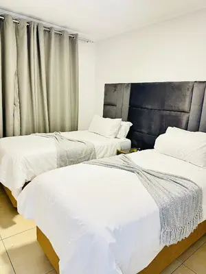 two beds in a room with white sheets at Elusive Haven in Nelspruit