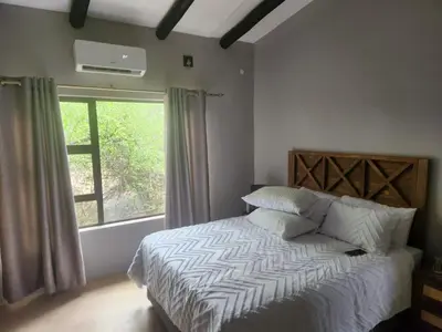 a bedroom with a bed with a large window at Neotha Villa Unit 2 in Marloth Park