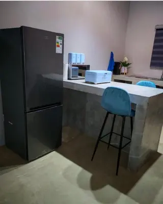 a kitchen with a counter with a blue bar stool at Neotha Villa Unit 2 in Marloth Park