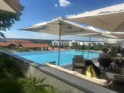a person sitting in a chair next to a swimming pool at Sunrise Waterfall at ELLIPSE in Midrand