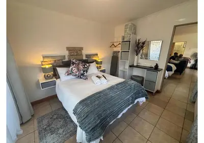 a bedroom with a large bed and a living room at Cottage of Grace in Benoni