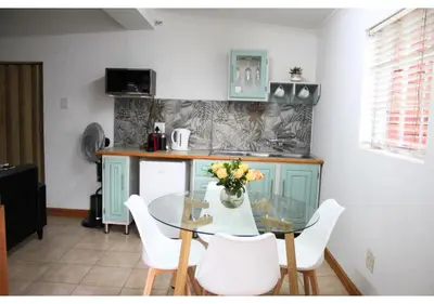 a kitchen with a glass table and white chairs at Cottage of Grace in Benoni