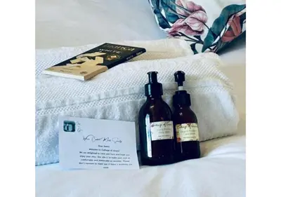two bottles of wine sitting on a bed with a book at Cottage of Grace in Benoni