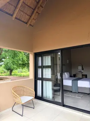 a bedroom with a bed and a chair on a patio at Fikani game lodge in Thabazimbi