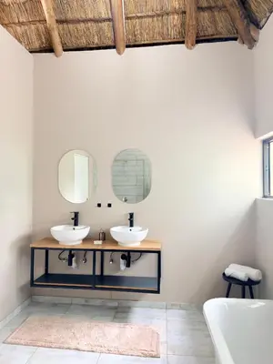 a bathroom with two sinks and a mirror at Fikani game lodge in Thabazimbi