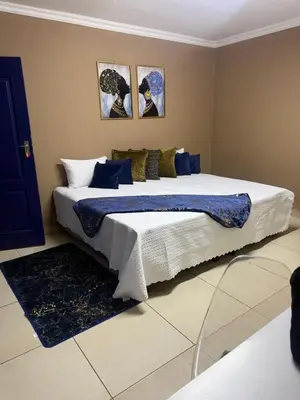 a bedroom with a large bed with blue and white sheets at VinVid Harties Guest House in Hartbeespoort