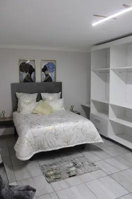 a bedroom with a bed with a white comforter at VinVid Harties Guest House in Hartbeespoort