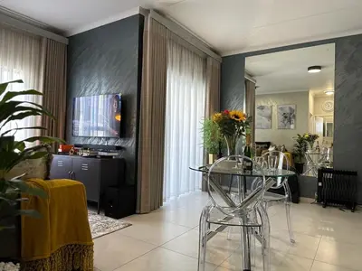 a living room with a glass table with chairs at Indulge in Elegance & Comfort in Midrand