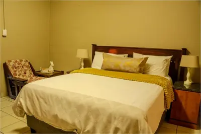 a bedroom with a large bed and a chair at 10 Kooralboom Self Catering Apartments in Nelspruit