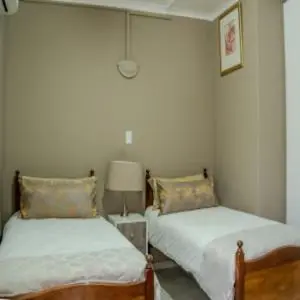a bedroom with two beds and a lamp at 10 Kooralboom Self Catering Apartments in Nelspruit