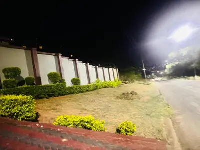 a fence with bushes and a street at night at BTV Villa in Hazyview