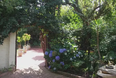 an archway with blue flowers in a garden at Sleep Eezy Cottages in Benoni