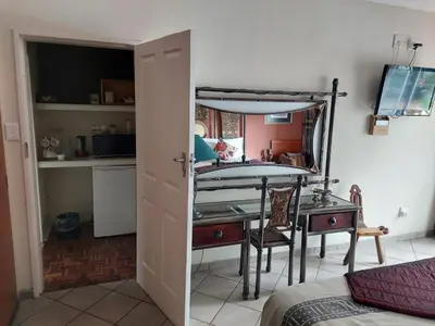 a room with a desk and a bed and a mirror at Sleep Eezy Cottages in Benoni