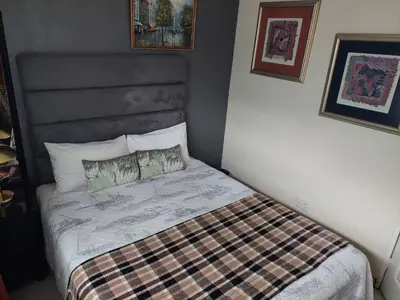 a small bedroom with a bed with a plaid blanket at Sleep Eezy Cottages in Benoni