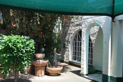a patio with potted plants and a green awning at Sleep Eezy Cottages in Benoni