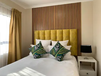 a bedroom with a bed with a yellow headboard and pillows at Waterfall Views in Midrand