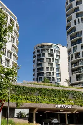 an apartment building with a green wall in front of two tall buildings at Luxe 4608 Ellipse Waterfall in Midrand