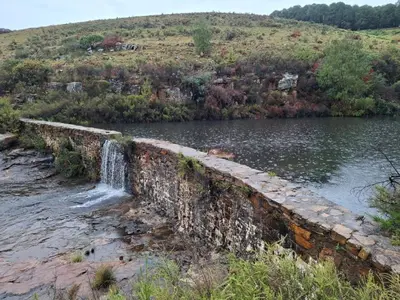 an old stone wall next to a body of water at AmaZeng chalet Wolf in Lydenburg