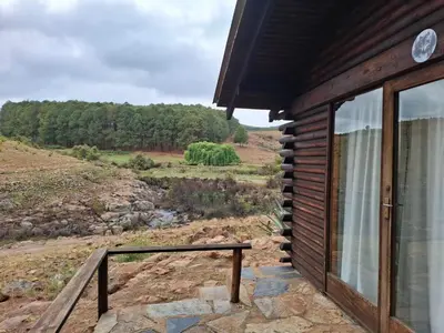 a cabin with a balcony with a view of a field at AmaZeng chalet Wolf in Lydenburg