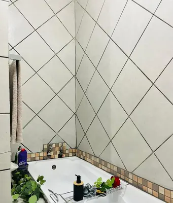 a bathroom with a tub and a tiled wall at Hlatsi Bushview Apartments & Safaris in Hazyview